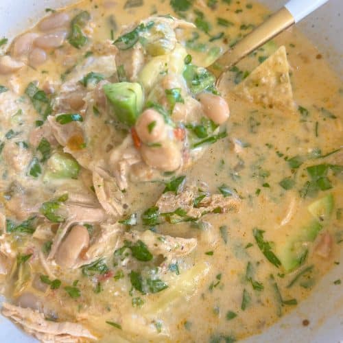 A bowl of white chicken chili all mixed up with the toppings
