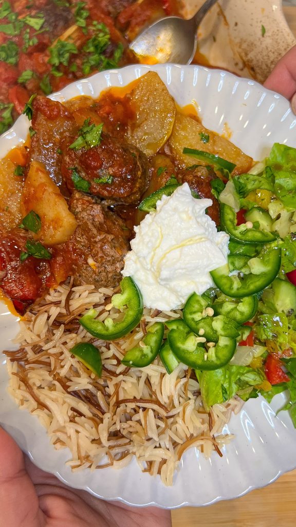 A plate of kafta bil sanieh ready to be enjoyed with rice, salad and yogurt