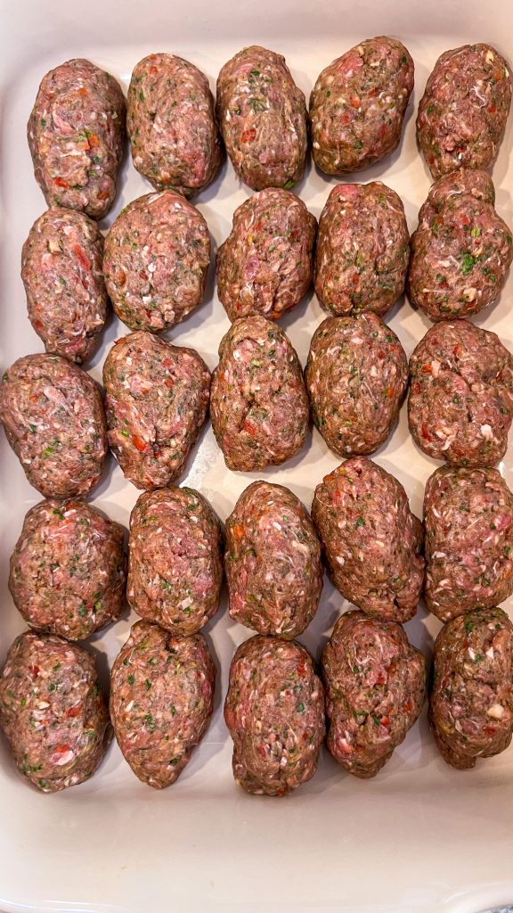 kafta kebabs arranged in a baking dish