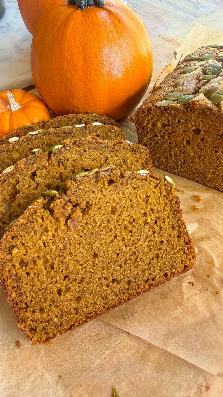 Pumpkin bread slices layered with pumpkins in the background