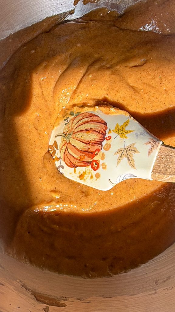 Pumpkin bread batter in a mixing bowl with a pumpkin spatula